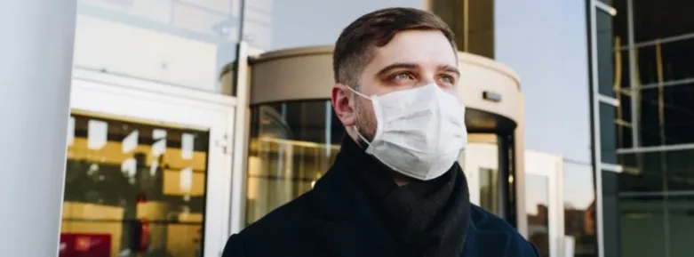 A man wearing a mask outside a building