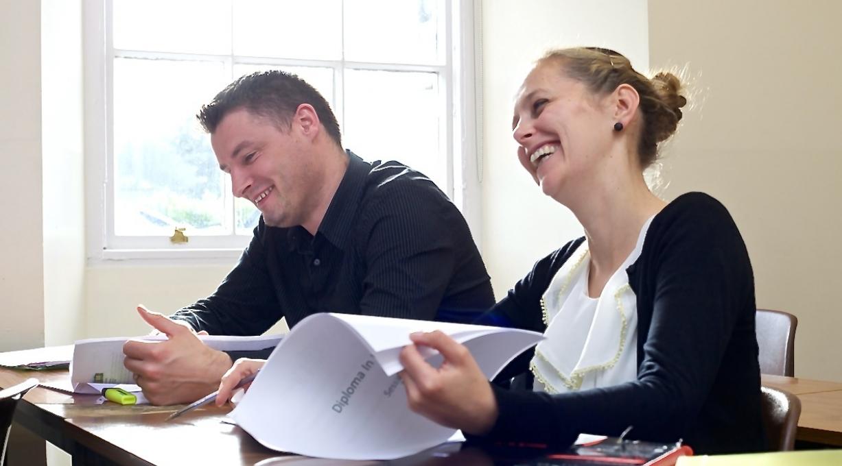Mature female and male student laughing in class